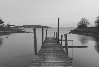bridge stretches across calm water with soft sunlight reflecting off the surface and a clear sky above creating a tranquil and expansive atmosphere
