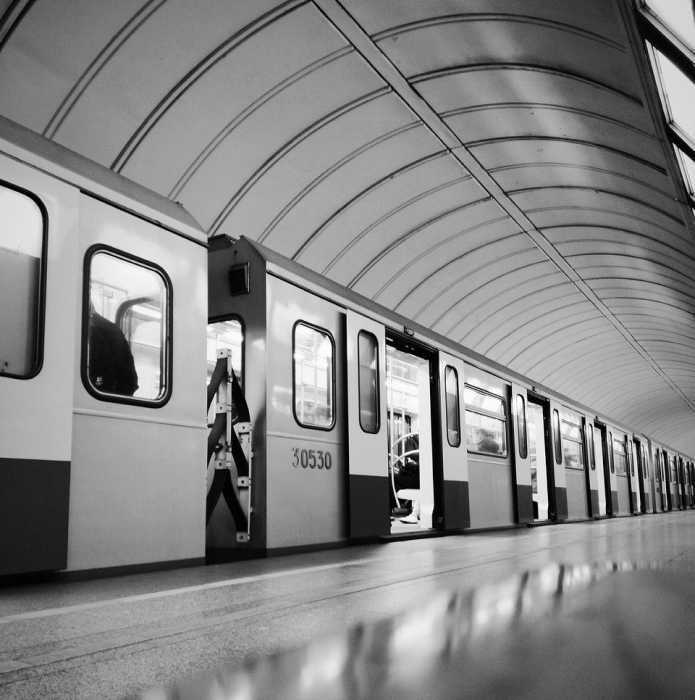 Subway platform with a single person waiting as a train approaches in a clean minimalist underground station with soft lighting and neutral tones creating a calm and contemplative atmosphere